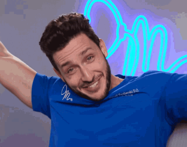 a smiling man wearing a blue shirt that says om
