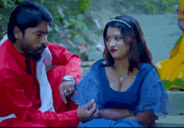 a man and a woman are sitting next to each other and talking . the woman is wearing a blue top .