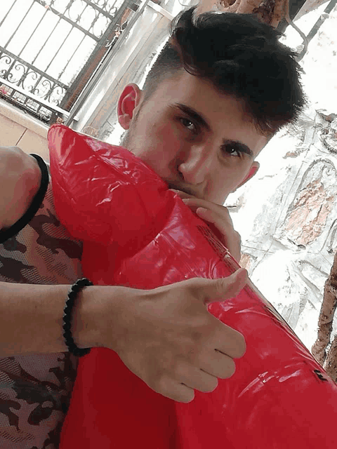 a man with a bracelet on his wrist is blowing up an inflatable red object