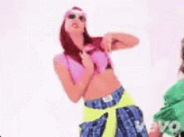 a woman in a pink top and neon yellow pants is dancing .