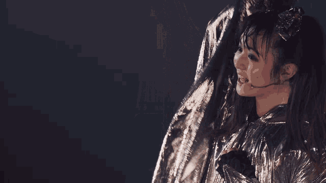 a woman with a microphone in her mouth is wearing a silver metallic outfit