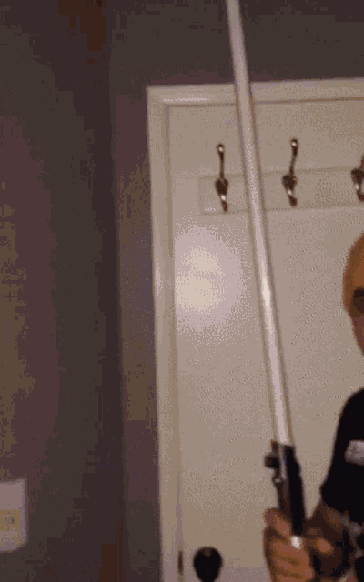 a man is holding a light saber in front of a door