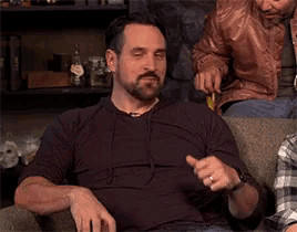a man with a beard is drinking a glass of whiskey