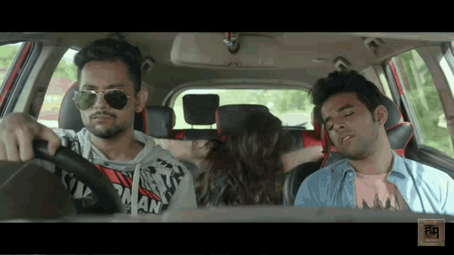 a man wearing sunglasses is driving a car with a woman in the back seat