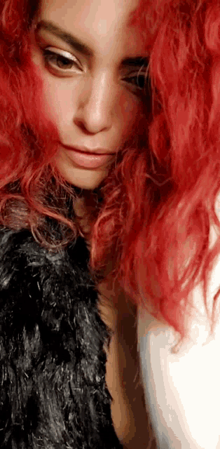 a woman with red hair is wearing a black fur jacket