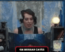 a woman sitting at a table reading a book called meghan caves