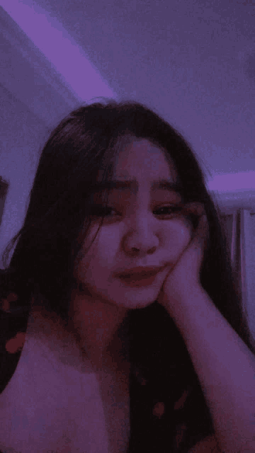 a girl with long hair is taking a selfie with her hand on her chin