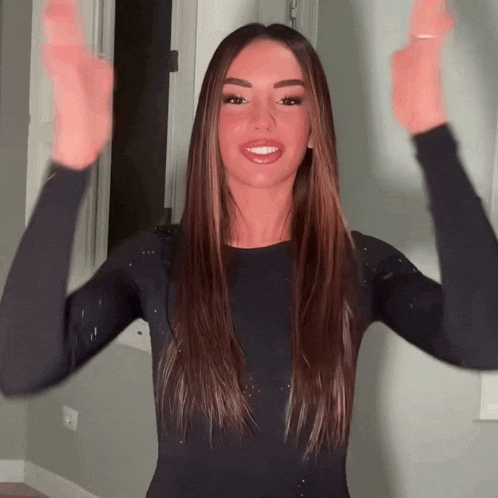 a woman in a black sweater is raising her hands in the air