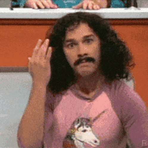 a man wearing a pink shirt with a unicorn on it is giving the middle finger