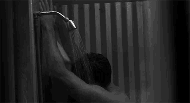 a man is taking a shower in a bathroom with a shower head .