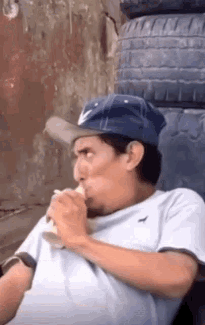 a man wearing a hat is eating a banana and drinking a beer .