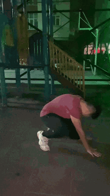 a man in a red shirt is doing push ups in a park