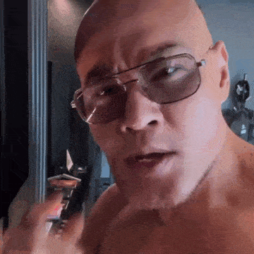 a shirtless bald man wearing sunglasses is making a funny face .