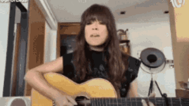 a woman is playing an acoustic guitar in a living room