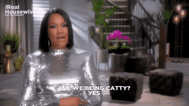 a woman in a silver dress says " are we being catty yes "