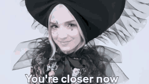 a woman wearing a black hat and a cape is smiling .