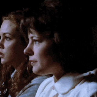 a couple of women are sitting next to each other in a dark room .