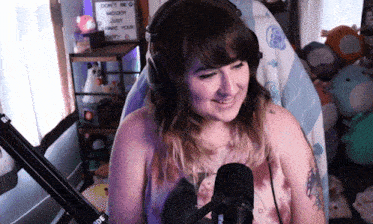 a woman wearing headphones is smiling in front of a sign that says do n't be moody just have your body