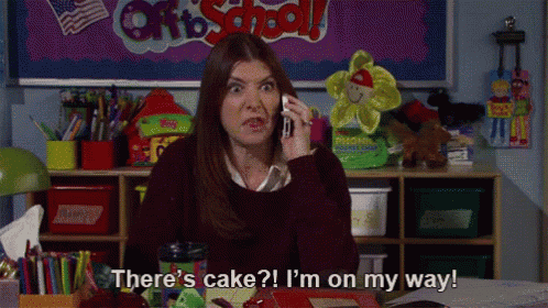 a woman is talking on a cell phone in a classroom and says there 's cake i 'm on my way