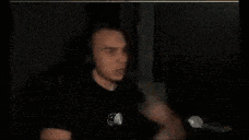 a blurry picture of a man in a dark room with a ghost behind him