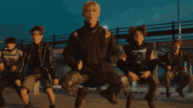 a group of young men are dancing on a concrete floor