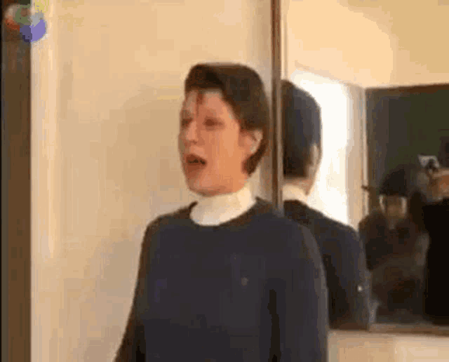 a woman is standing in front of a mirror and looking at herself .