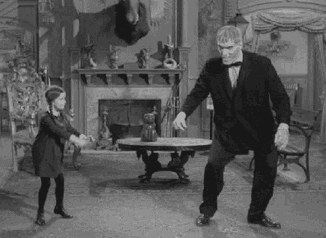 a black and white photo of a man and a little girl dancing in a living room .