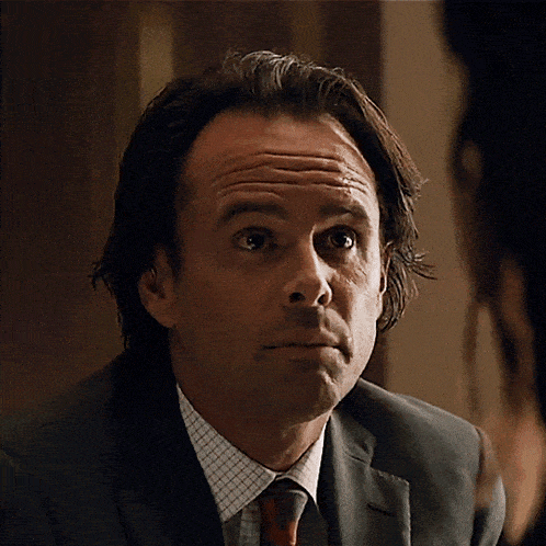 a man in a suit and tie is looking at the camera