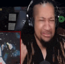 a man wearing headphones is sitting in front of a microphone and making a funny face .