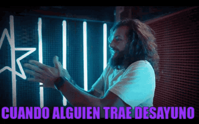 a man clapping in front of a neon sign that says cuando alguien trae desayuno