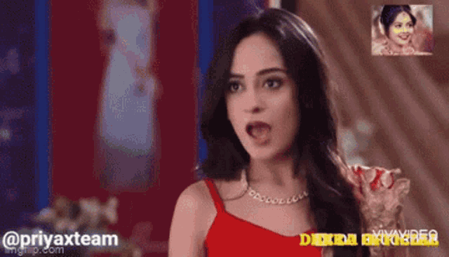 a woman in a red top and necklace is making a funny face