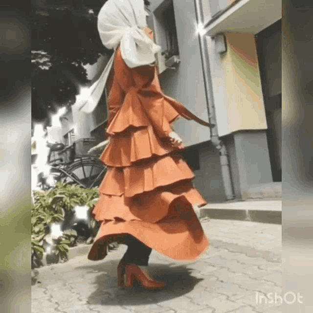 a woman wearing a hijab and a ruffled orange dress