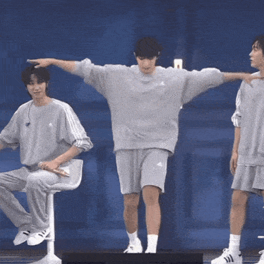 a man in a grey adidas sweatshirt is standing on one leg