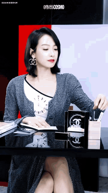 a woman sitting at a table with a cosmo logo on the bottom right