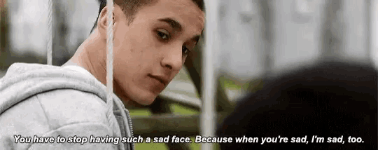 a young man is sitting on a swing and talking to another person .