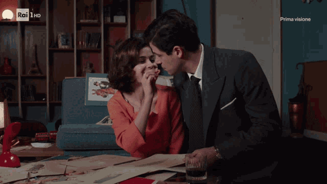 a man kisses a woman on the cheek in front of a tv screen that says rai 1 hd