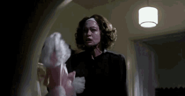 a woman in a black dress is holding a pink stuffed animal in a dark room .