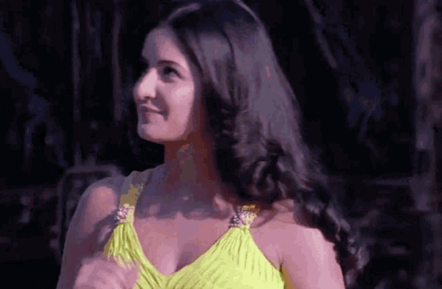 a woman in a yellow dress is smiling and looking away from the camera