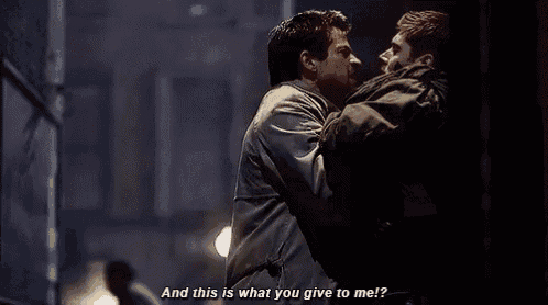 two men are standing next to each other in a dark room and talking to each other .