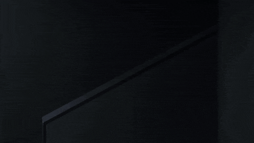 a man peeking out from behind a staircase railing in a dark room