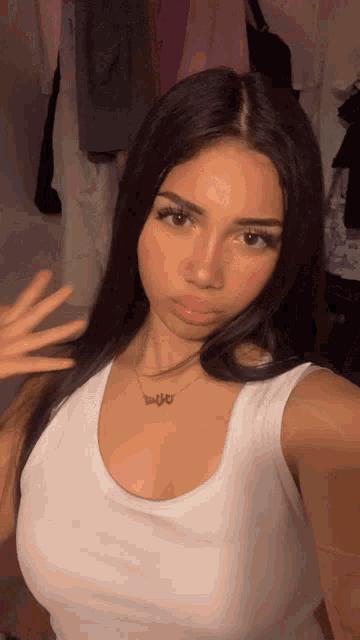 a woman wearing a white tank top and a necklace that says ' eulo '
