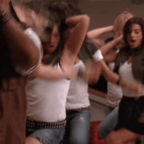 a group of young women are dancing together in a room