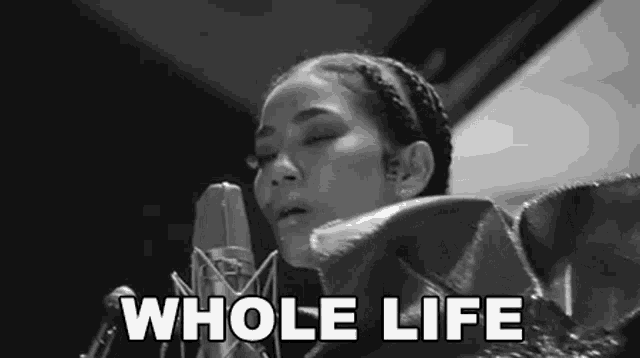 a black and white photo of a woman singing into a microphone with the words `` whole life '' .