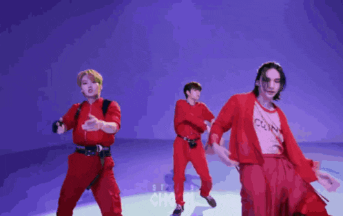 a group of young men in red outfits are dancing on a stage .