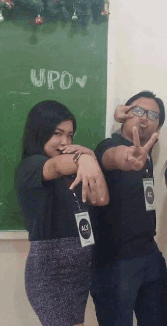 a man and a woman are posing for a picture in front of a green board that says upov