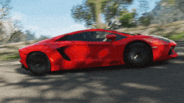a red sports car driving down a road with trees in the background