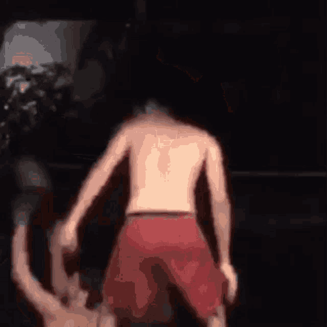 a shirtless man in red shorts is standing in front of a crowd .