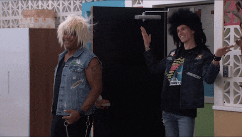 a man wearing a black shirt that says ' nirvana ' on it stands next to another man