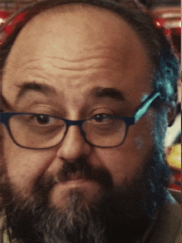 a man with glasses and a beard is looking at the camera
