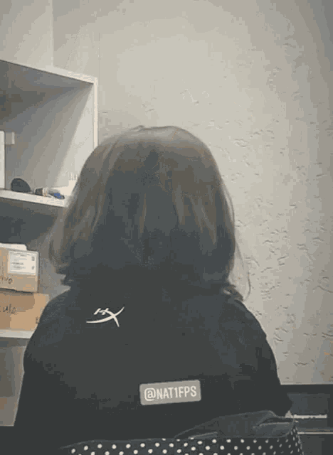 a person wearing a black shirt that says @ nat1fps on the back